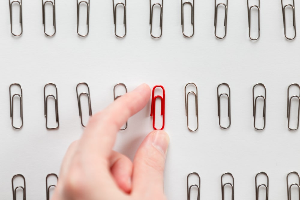 hand picking among-metal-paperclips-one-red-different from others